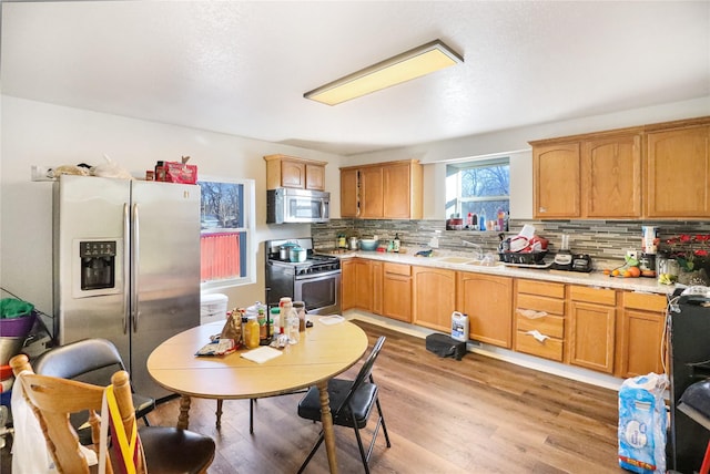 kitchen featuring sink, decorative backsplash, light hardwood / wood-style flooring, and appliances with stainless steel finishes