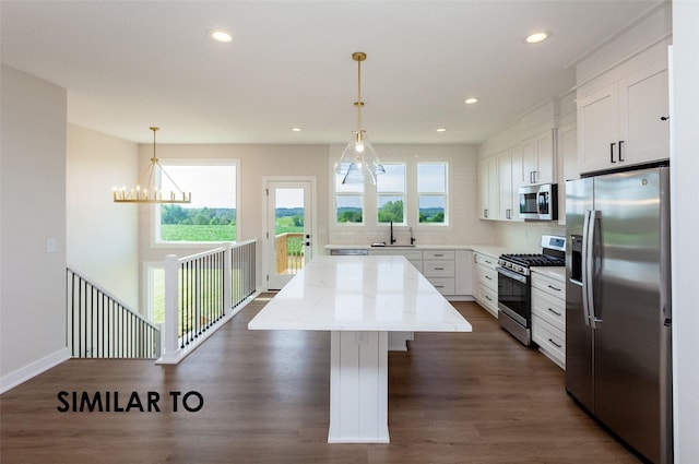 kitchen with white cabinetry, appliances with stainless steel finishes, a kitchen island, pendant lighting, and a healthy amount of sunlight