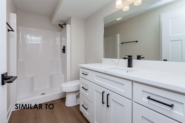 bathroom featuring vanity, wood-type flooring, toilet, and a shower