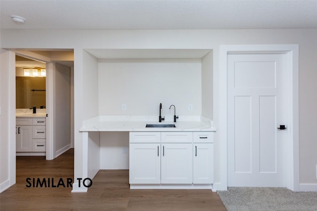 bar with white cabinetry, wood-type flooring, light stone countertops, and sink