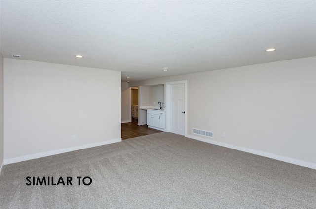 carpeted spare room with sink and a textured ceiling