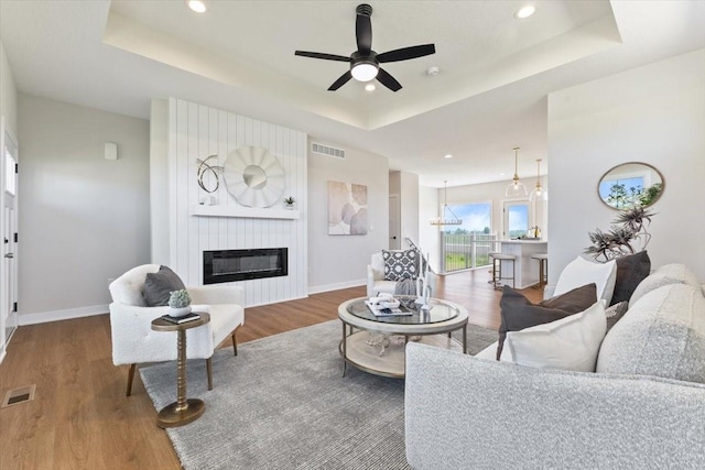 612 W Walnut Pl, Norwalk, IA 50211 - living area featuring a raised ceiling, wood finished floors, a ceiling fan, a large fireplace, and recessed lighting