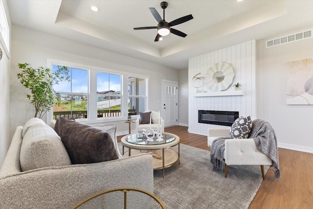 612 W Walnut Pl, Norwalk, IA 50211 - living area featuring a raised ceiling, wood finished floors, a fireplace, a ceiling fan, and recessed lighting