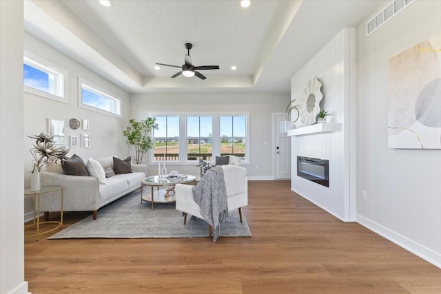 612 W Walnut Pl, Norwalk, IA 50211 - living area with ceiling fan, a raised ceiling, a fireplace, wood finished floors, and recessed lighting
