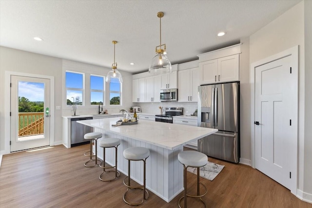 612 W Walnut Pl, Norwalk, IA 50211 - kitchen featuring stainless steel appliances, a breakfast bar, white cabinetry, a kitchen island, and wood finished floors