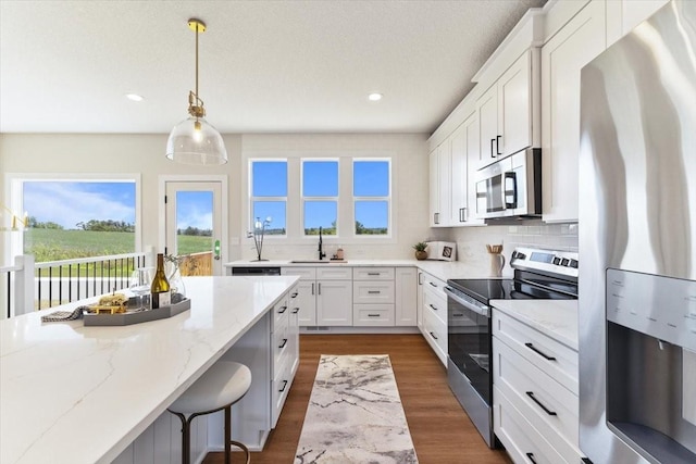 612 W Walnut Pl, Norwalk, IA 50211 - kitchen featuring appliances with stainless steel finishes, light stone countertops, white cabinetry, dark wood-style floors, and recessed lighting