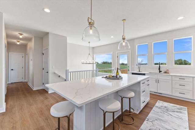 612 W Walnut Pl, Norwalk, IA 50211 - kitchen featuring a kitchen island, white cabinetry, a breakfast bar, light wood finished floors, and recessed lighting
