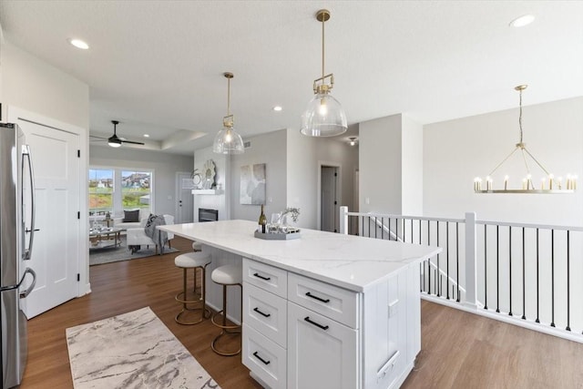 612 W Walnut Pl, Norwalk, IA 50211 - kitchen with stainless steel refrigerator, white cabinets, a kitchen island, a chandelier, and open floor plan