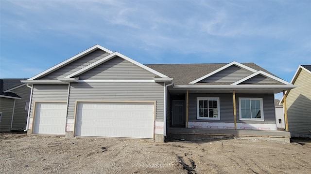 view of front of home with roof with shingles, a garage, and dirt driveway