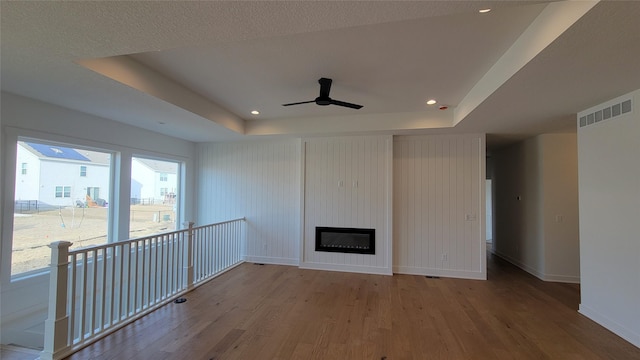 unfurnished living room with a raised ceiling, wood finished floors, baseboards, and a large fireplace