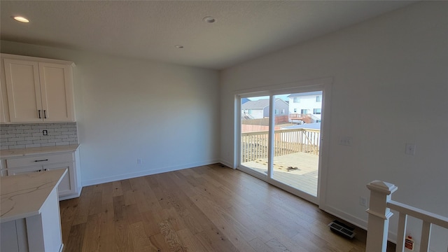 unfurnished dining area featuring recessed lighting, light wood-style floors, and baseboards