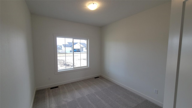 empty room featuring light carpet, visible vents, and baseboards