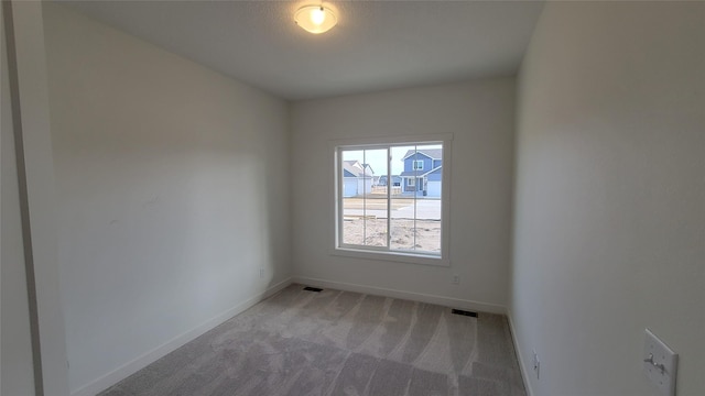 unfurnished room featuring visible vents, baseboards, and light colored carpet