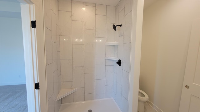 full bathroom with toilet, tiled shower, and baseboards