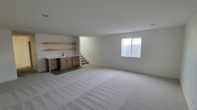 interior space featuring carpet flooring, baseboards, and a sink