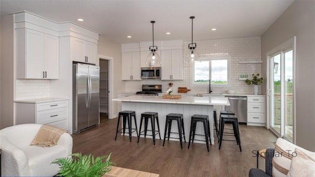 kitchen with a center island, appliances with stainless steel finishes, dark hardwood / wood-style floors, pendant lighting, and white cabinets