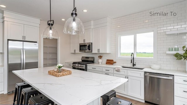 kitchen featuring white cabinetry, sink, a kitchen island, and appliances with stainless steel finishes