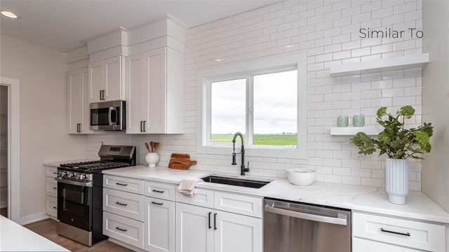 kitchen featuring sink, decorative backsplash, white cabinets, and appliances with stainless steel finishes