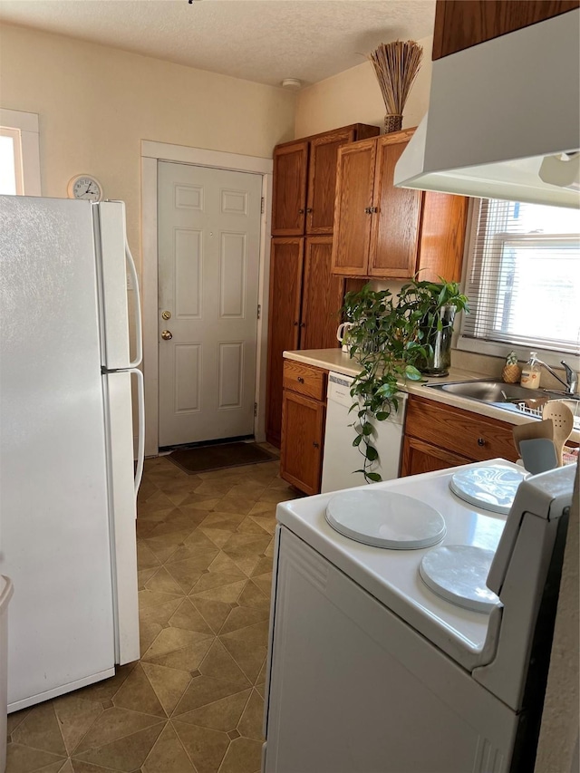 kitchen with sink, white appliances, a textured ceiling, and premium range hood