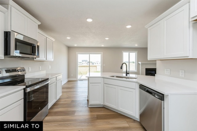 kitchen featuring stainless steel appliances, white cabinetry, sink, and light hardwood / wood-style flooring