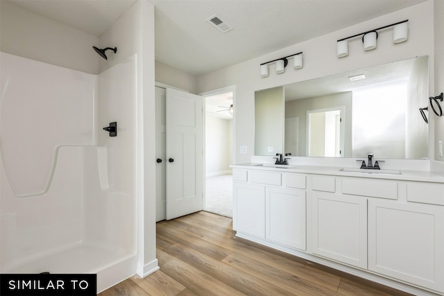 bathroom with hardwood / wood-style flooring, vanity, and walk in shower