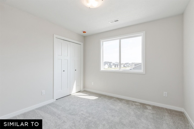 unfurnished bedroom featuring light colored carpet and a closet