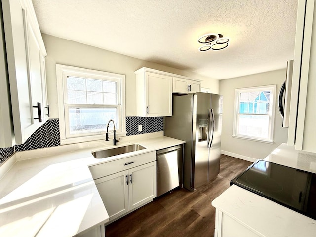 kitchen featuring stainless steel appliances, sink, decorative backsplash, and white cabinets