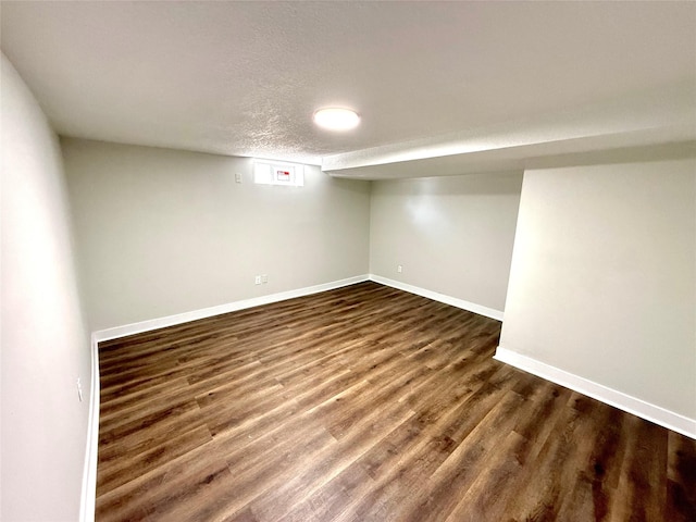 basement featuring dark wood-type flooring and a textured ceiling