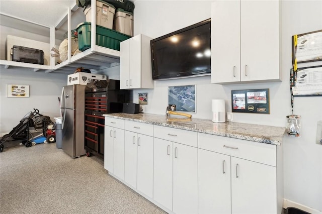 kitchen featuring white cabinetry, stainless steel fridge, and light stone counters