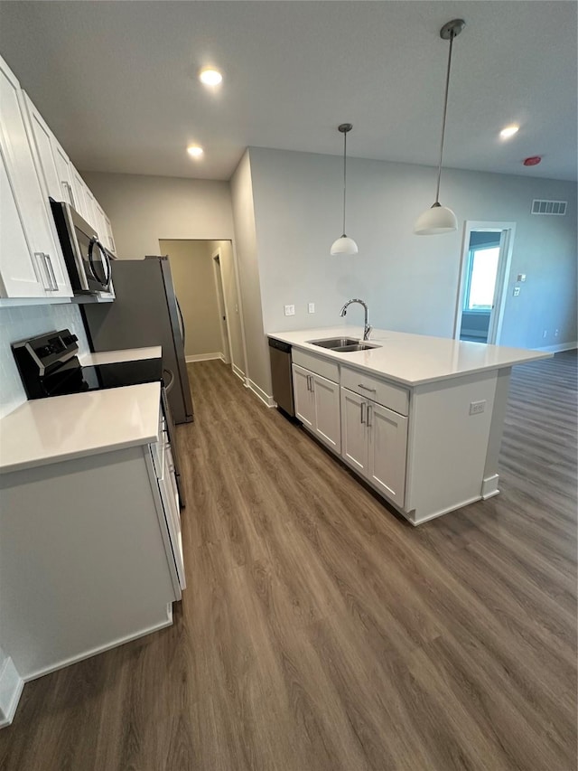 kitchen featuring dark wood-type flooring, sink, hanging light fixtures, appliances with stainless steel finishes, and white cabinets