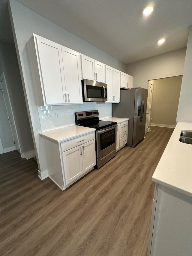 kitchen with white cabinetry, decorative backsplash, dark wood-type flooring, and appliances with stainless steel finishes