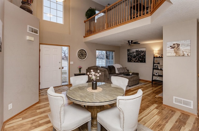 dining space featuring a towering ceiling, light hardwood / wood-style floors, and ceiling fan