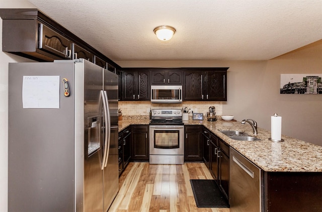 kitchen featuring dark brown cabinetry, stainless steel appliances, sink, and light hardwood / wood-style flooring