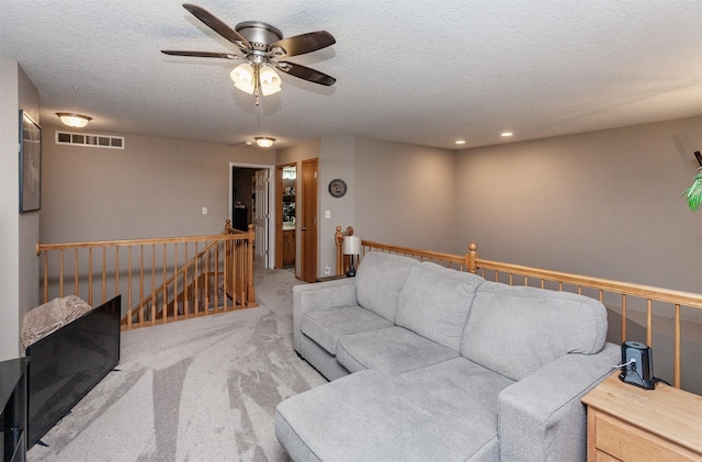 carpeted living room with ceiling fan and a textured ceiling