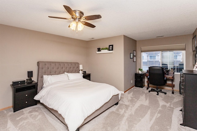 bedroom featuring ceiling fan, light colored carpet, and a textured ceiling