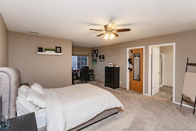 bedroom with ceiling fan, a walk in closet, light carpet, and a textured ceiling