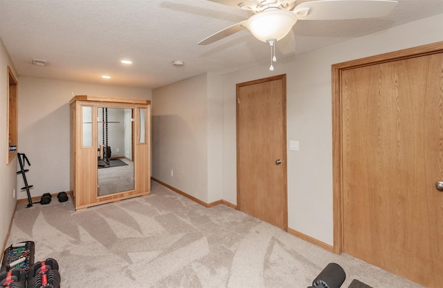 unfurnished bedroom featuring light carpet, ceiling fan, and a textured ceiling