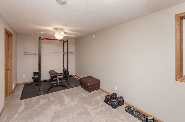 workout area with ceiling fan, carpet flooring, and a textured ceiling