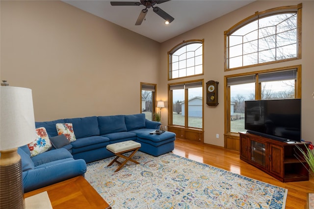 living room with high vaulted ceiling, light wood-type flooring, and a ceiling fan