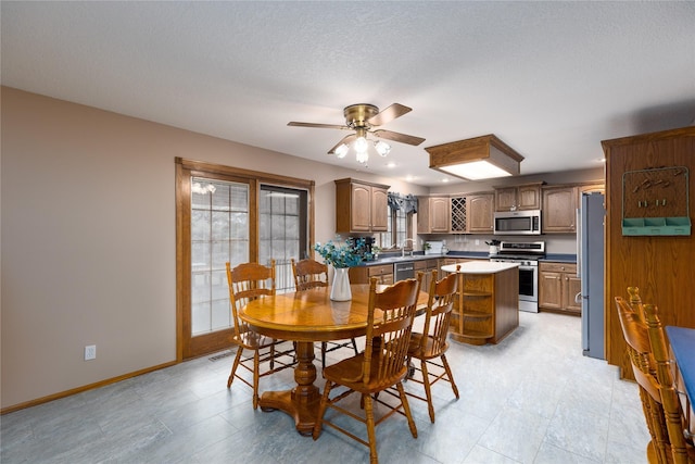 dining room featuring visible vents, baseboards, a textured ceiling, and a ceiling fan