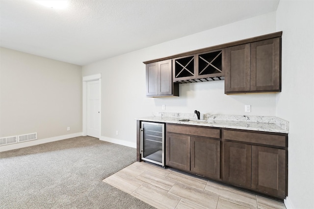 bar with sink, wine cooler, and dark brown cabinetry