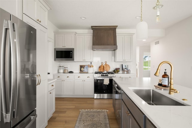 1083 NW 35th St, Grimes, IA 50111 - kitchen featuring stainless steel appliances, a sink, custom range hood, wood finished floors, and pendant lighting