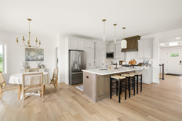 1083 NW 35th St, Grimes, IA 50111 - kitchen with appliances with stainless steel finishes, a sink, premium range hood, a chandelier, and light wood-type flooring