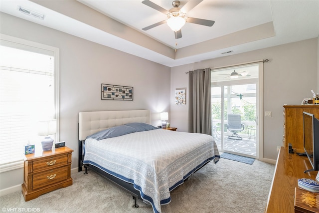 carpeted bedroom featuring access to exterior, a raised ceiling, and ceiling fan