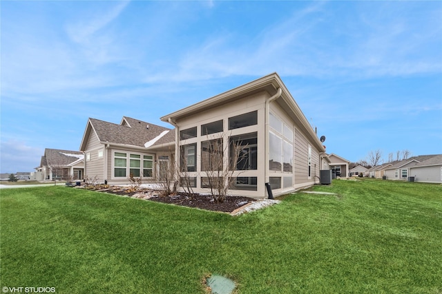 rear view of property featuring a sunroom and a lawn