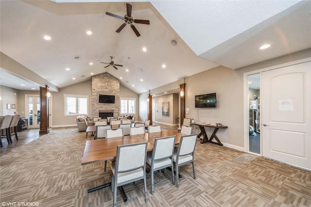 carpeted dining space with a stone fireplace, high vaulted ceiling, and ceiling fan