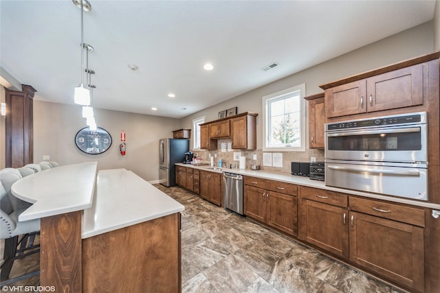 kitchen with pendant lighting, backsplash, a kitchen island, stainless steel appliances, and a kitchen bar