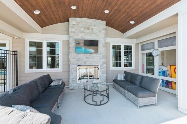 carpeted living room featuring vaulted ceiling, wooden ceiling, and an outdoor stone fireplace