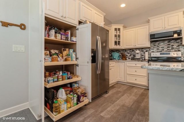 kitchen with tasteful backsplash, stainless steel appliances, dark hardwood / wood-style floors, and light stone countertops