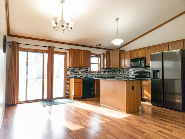 kitchen featuring pendant lighting, decorative backsplash, black appliances, and a kitchen island